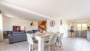 A modern living space with a dining area, a sofa, and a kitchen.
