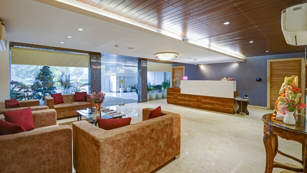 A modern lobby with plush seating, a reception desk, and large windows offering a view of the outdoors. - Hotel 91 Huda Premier (Gurugram)