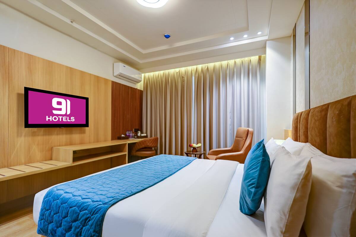 A hotel room with a bed, a TV, a desk, and a chair.