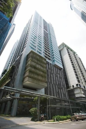 Un immeuble de grande hauteur au design moderne, doté d’une façade en verre et d’une entrée imposante surmontée d’un auvent.