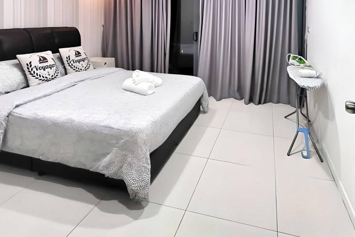 Une chambre moderne avec un grand lit, des rideaux gris, une petite table de chevet et un appareil de climatisation.