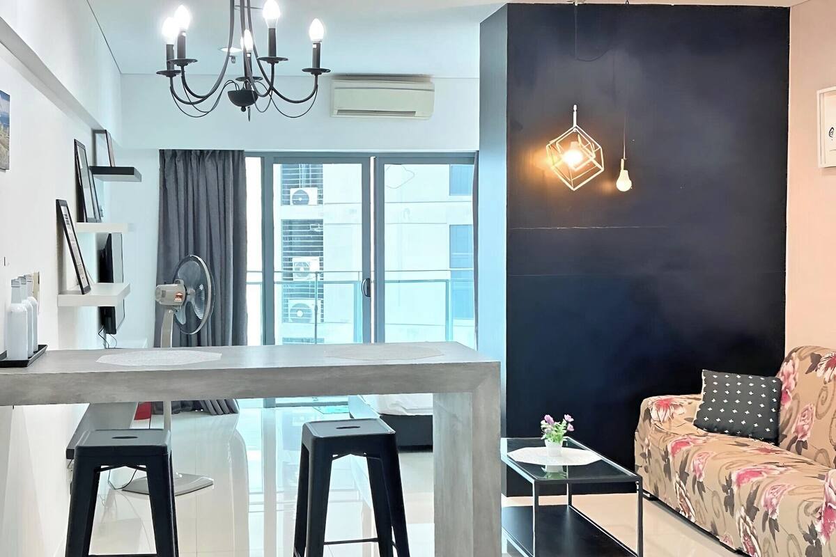Un salon moderne comprenant un canapé, une table basse et un coin repas avec une table et deux tabourets.