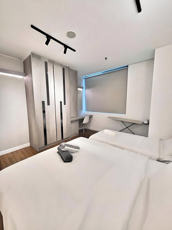 A modern hotel room with a bed, a desk, and a wardrobe.