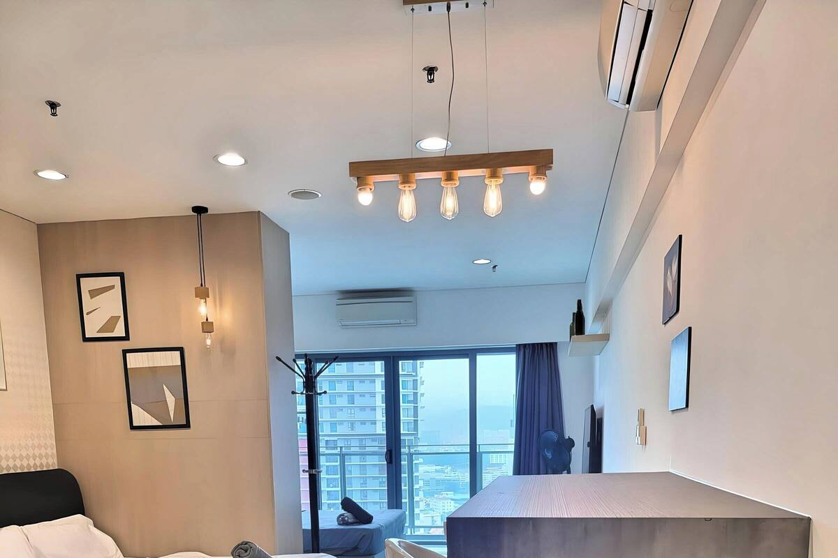Une chambre d’hôtel moderne dotée d’un grand lit, d’un coin salon avec vue et d’un mur décoratif en béton.