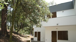 A white building with two doors and windows, surrounded by trees and a stone pathway. - Renovated two-bedroom flat in Rosolina Mare (Rosolina Mare)