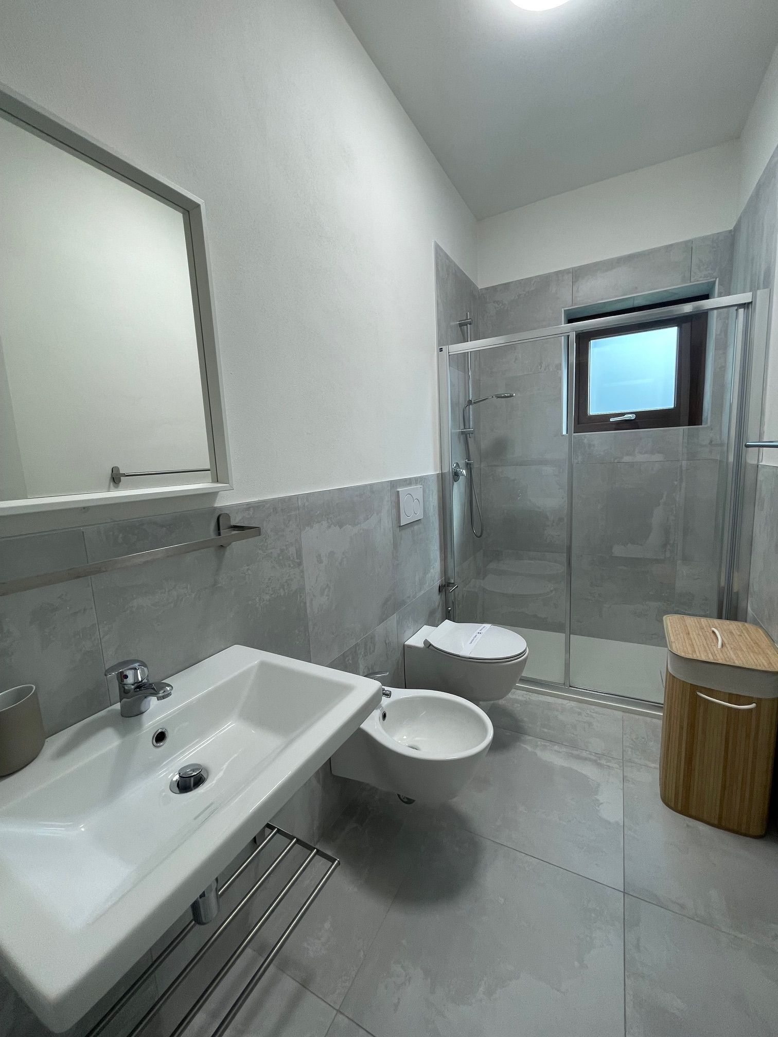Een moderne badkamer met een wastafel, toilet en douche.