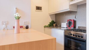 A modern kitchen with a wooden countertop, a gas stove, a microwave, and a toaster. - MOT Rentals + Ravignani 2100 - Lux Loft Terrace & Jacuzzi (Buenos Aires)