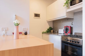 A modern kitchen with a wooden countertop, a gas stove, a microwave, and a toaster.