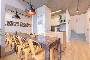 A modern kitchen with white cabinets, a wooden dining table, and yellow chairs. - MOT Rentals + Ravignani 2100 - Lux Loft Terrace & Jacuzzi (Buenos Aires)