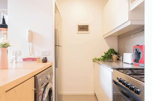Una cocina compacta con lavadora, estufa y tostadora.