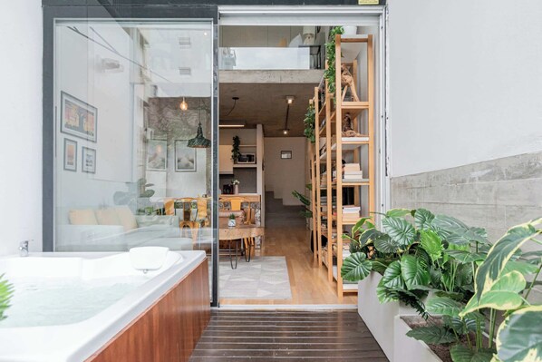A modern interior with a glass door leading to a living area, a wooden staircase, and a large plant.