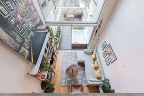 A modern interior with a glass ceiling, a cozy seating area, a wooden coffee table, and a bookshelf. - MOT Rentals + Ravignani 2100 - Lux Loft Terrace & Jacuzzi (Buenos Aires)
