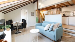 Et loftstudios med spiseplads, sofa og køkken.