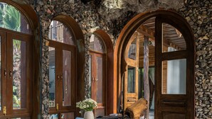 A rustic room with a stone wall, wooden furniture, and a large log table. - AiLee Villa & Hotel Tamcoc (Nam Hoa Lu)