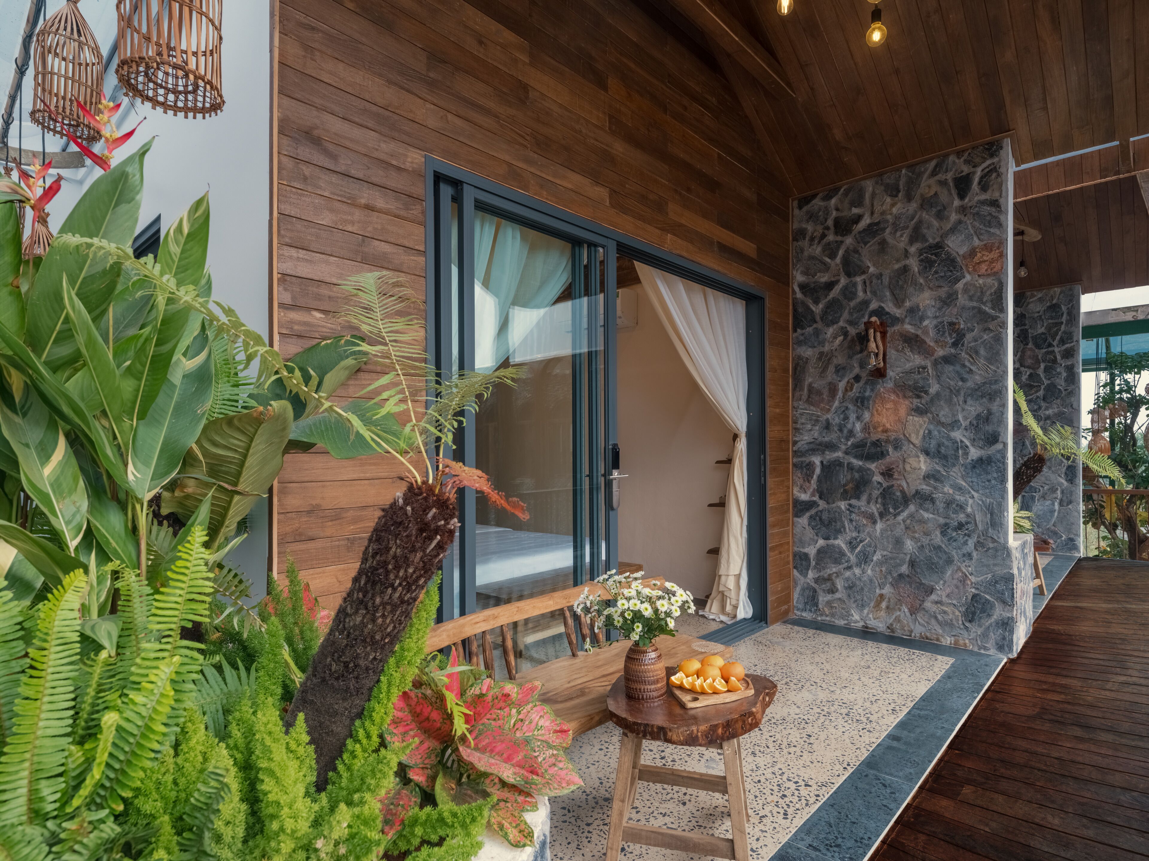 A modern interior with a wooden floor, a stone wall, and a glass door leading to a room.