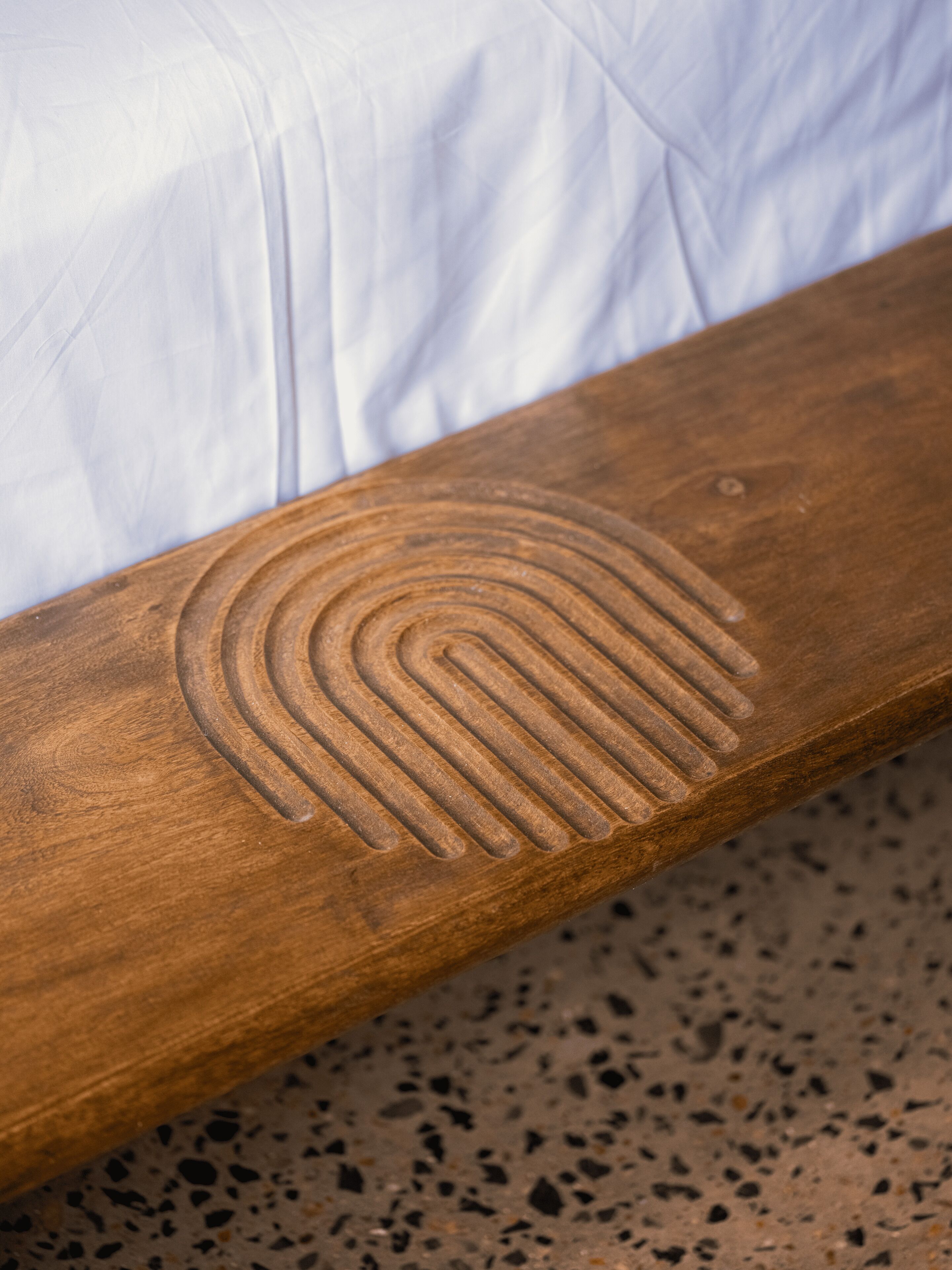A wooden bench with a circular carved design.