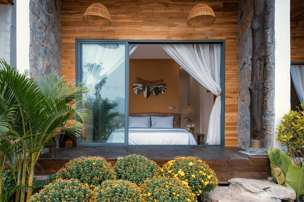 A bedroom with a large window, a bed, and a view of the outdoors.