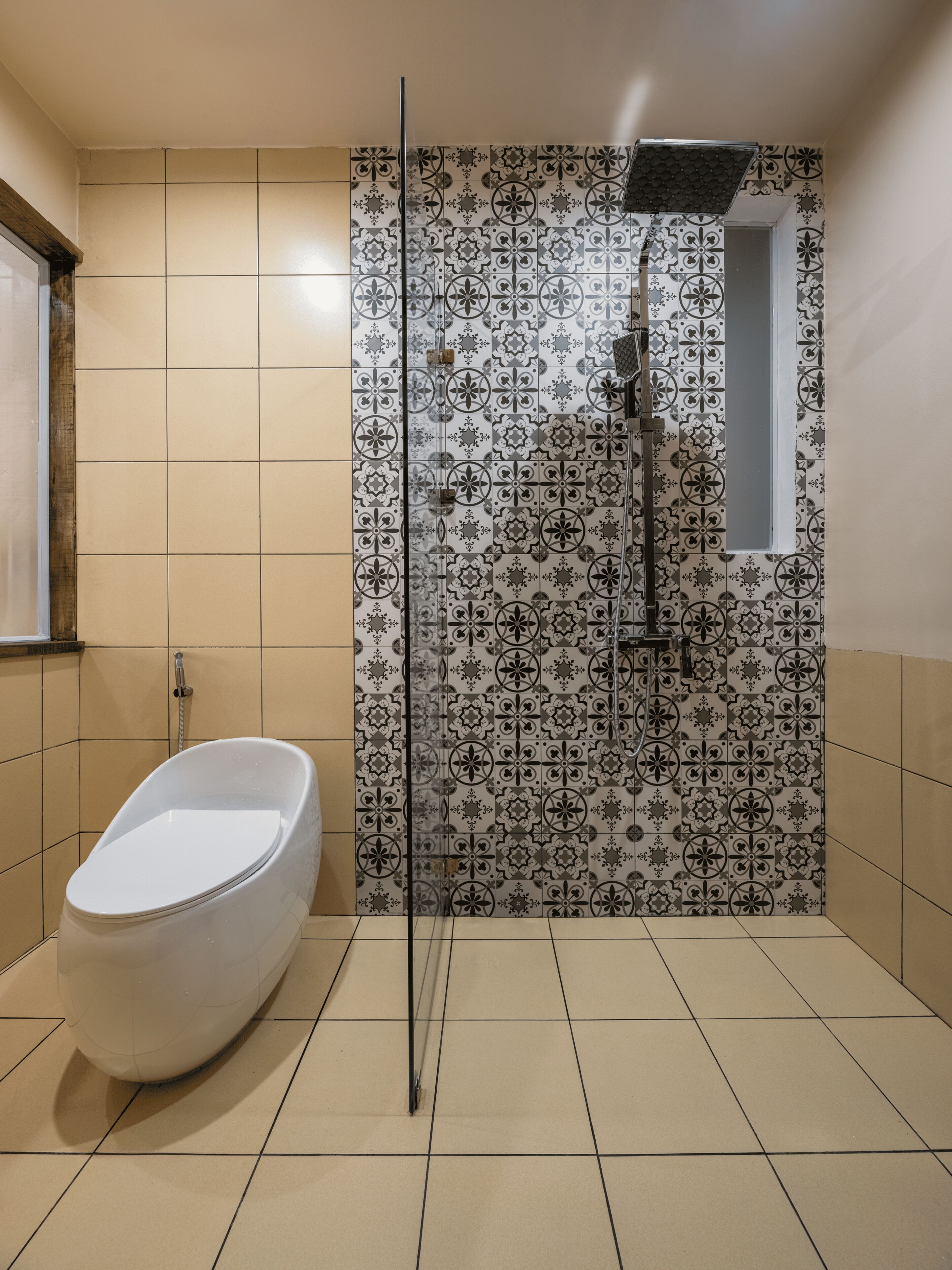 A bathroom with a freestanding bathtub, a shower with a rain showerhead, and patterned tiles on the walls.