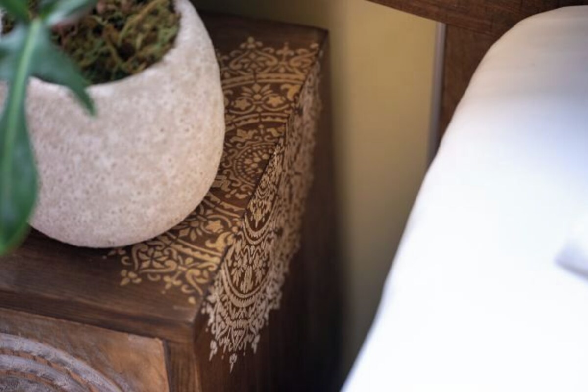 A potted plant on a wooden surface with a patterned cushion.