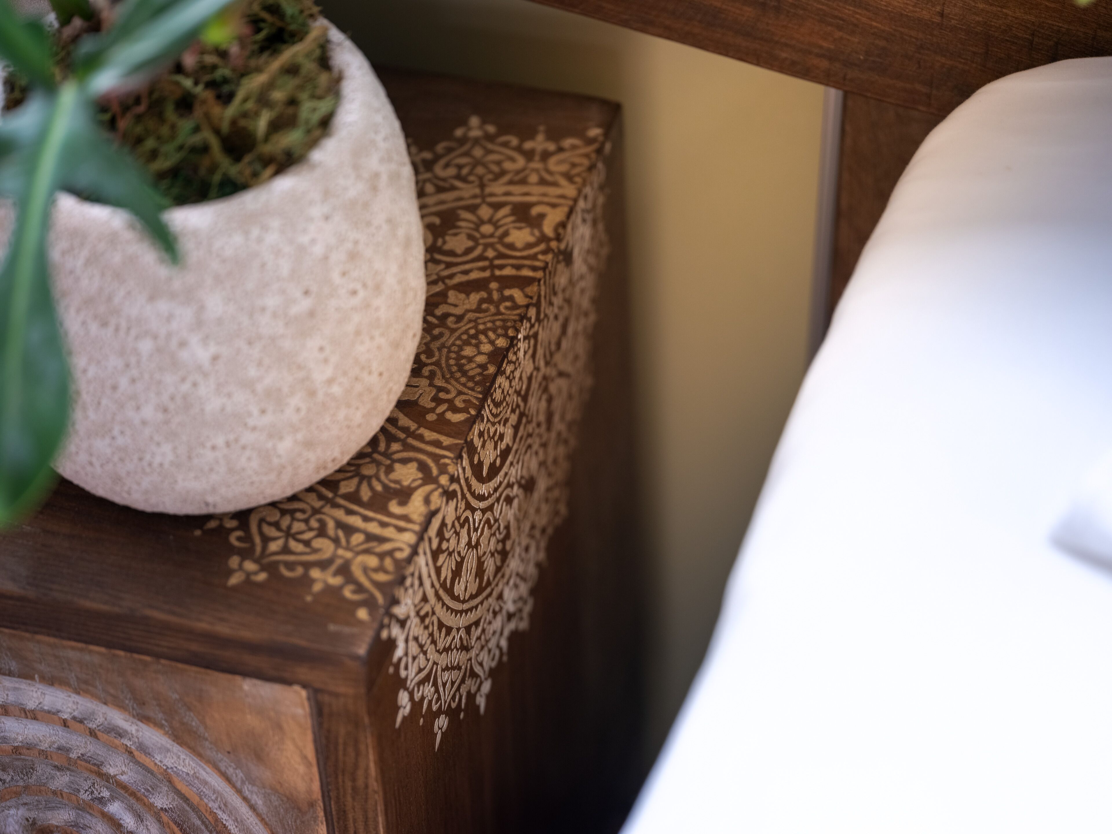 A close-up of a wooden surface with a decorative carved panel and a potted plant.