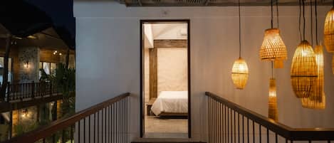 A staircase leading to a bedroom with a bed, a pool, and hanging lamps.