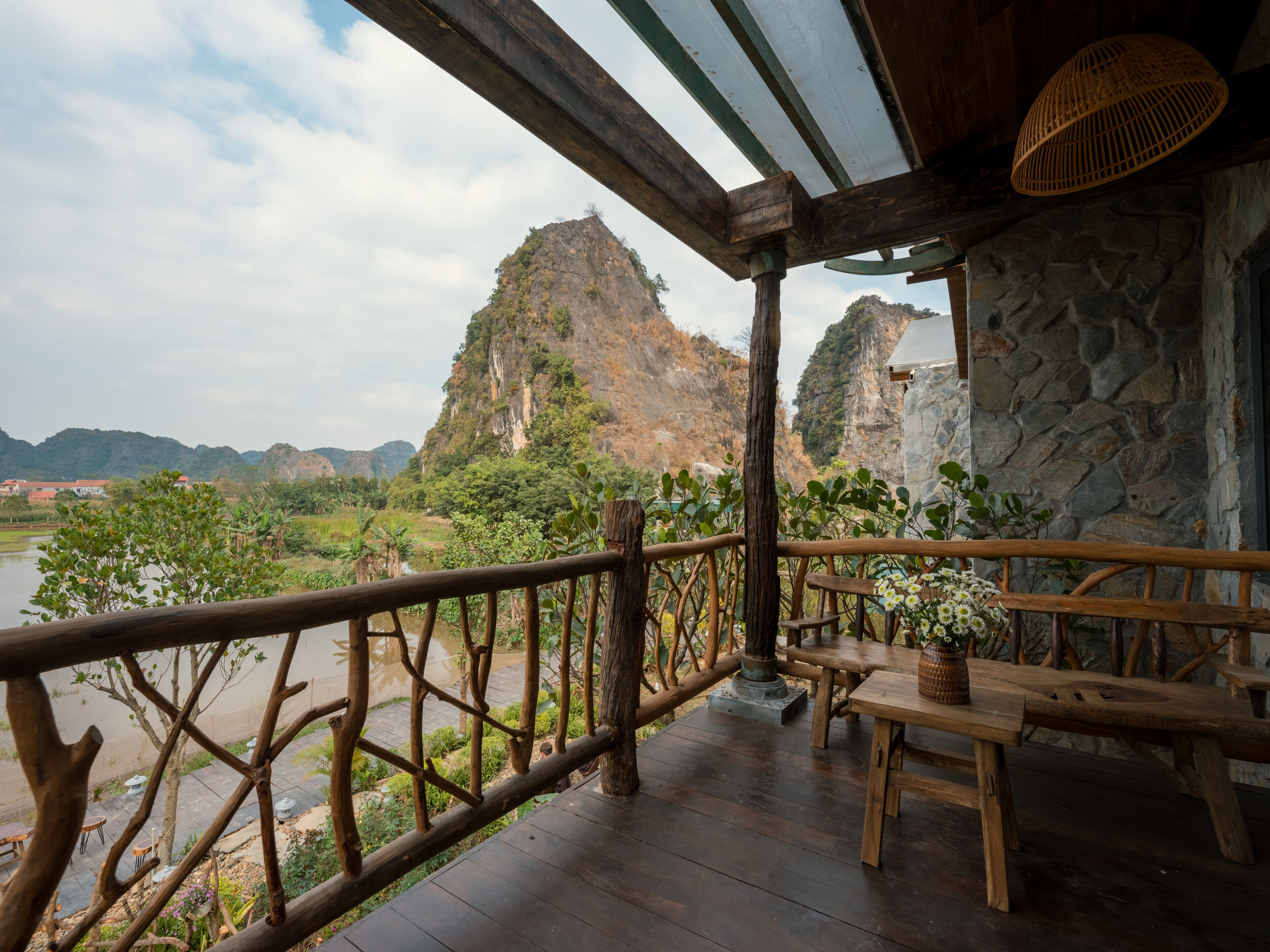 Eine Holzterrasse mit einer Steinmauer und Blick auf eine gebirgige Landschaft.