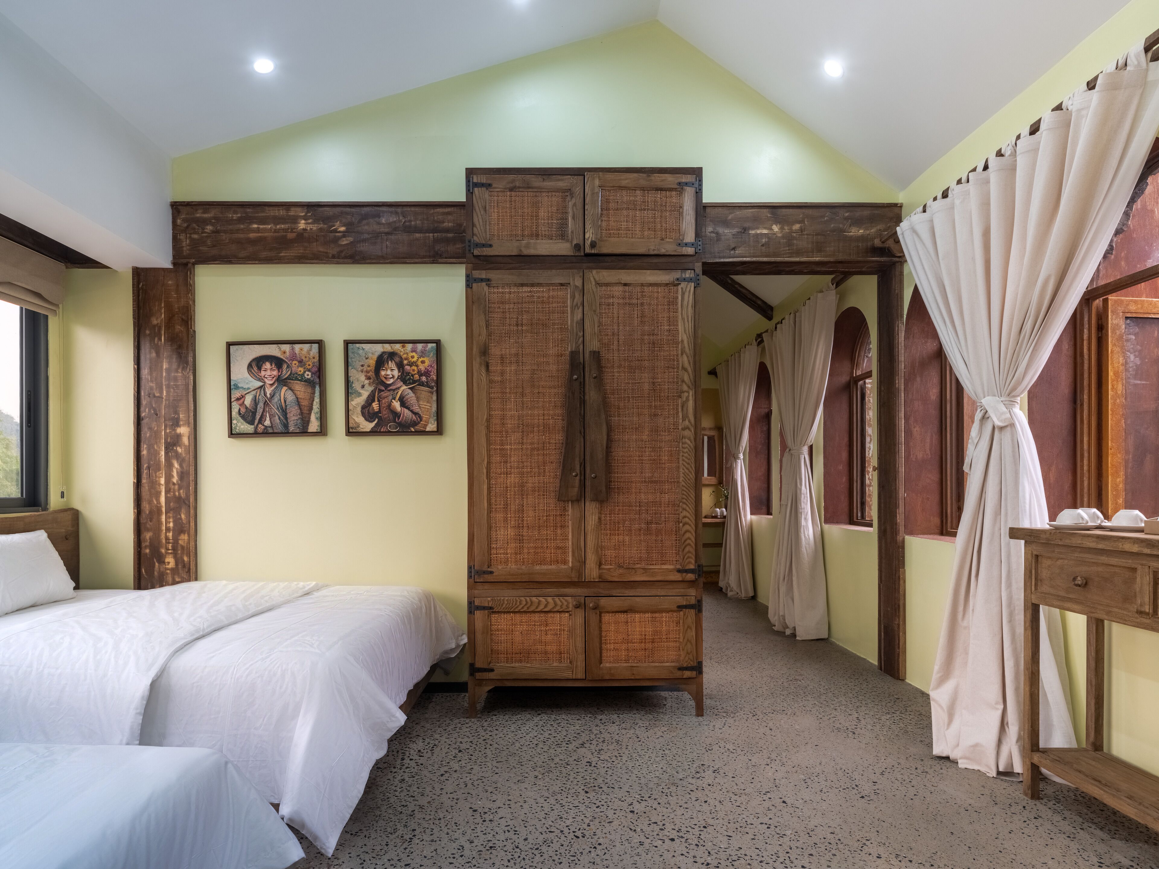 A bedroom with two beds, a wooden wardrobe, and two framed pictures on the wall.