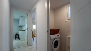 A laundry room with a washing machine, a basket on top, and a small window. - Two bedroom  in Spain, Santander (Santander)