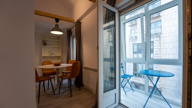 A modern apartment with a dining area, a blue folding table outside, and a view of the city through large windows. - Two bedroom  in Spain, Santander (Santander)