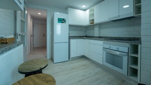 A compact kitchen with white cabinets, a built-in oven, and a refrigerator. - Two bedroom  in Spain, Santander (Santander)