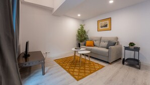 A modern living room with a grey sofa, a small round table, a plant, and a painting on the wall. - Two bedroom  in Spain, Santander (Santander)