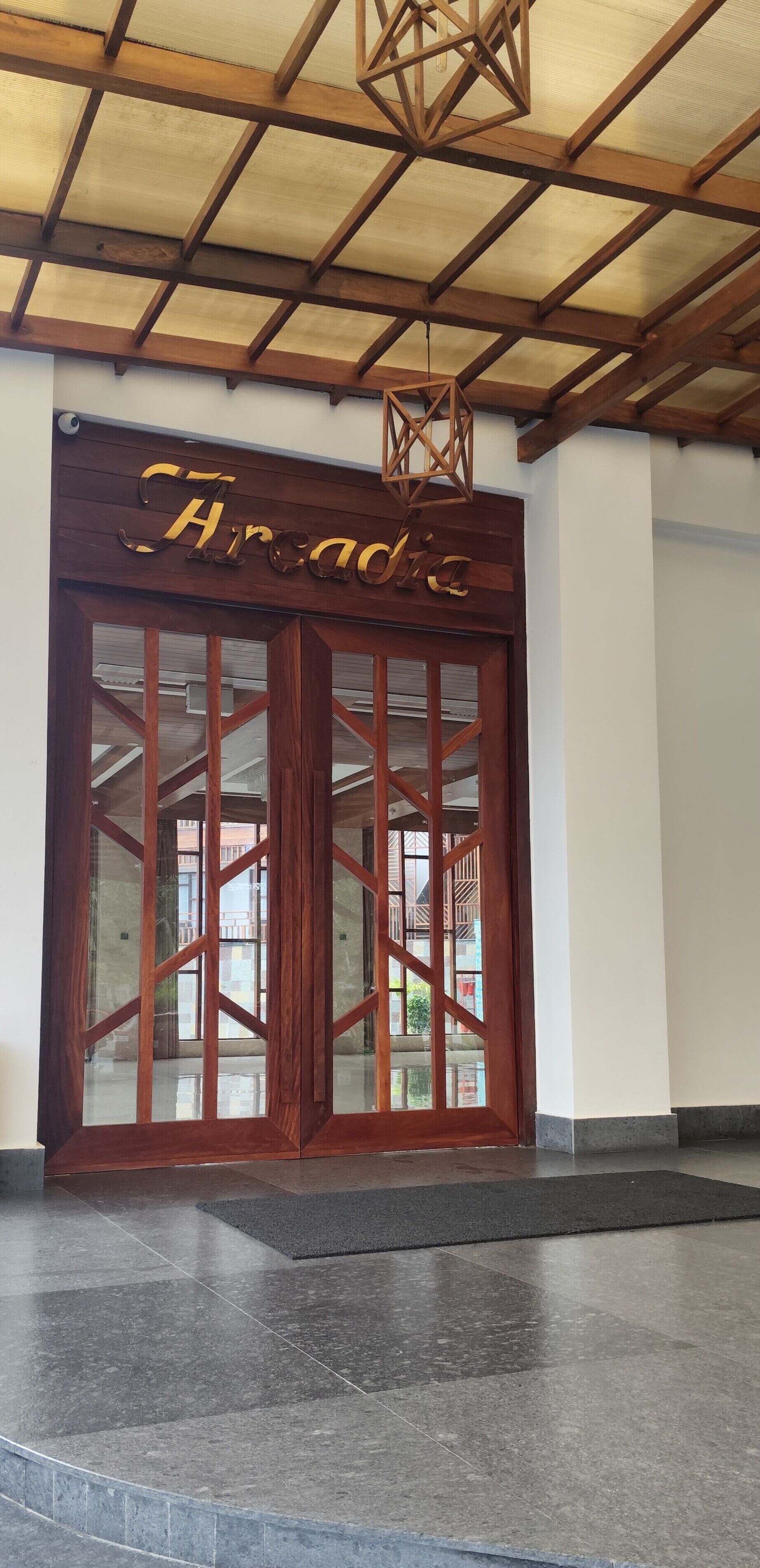 A wooden entrance with a glass door and the name "Arcadia" in gold lettering.
