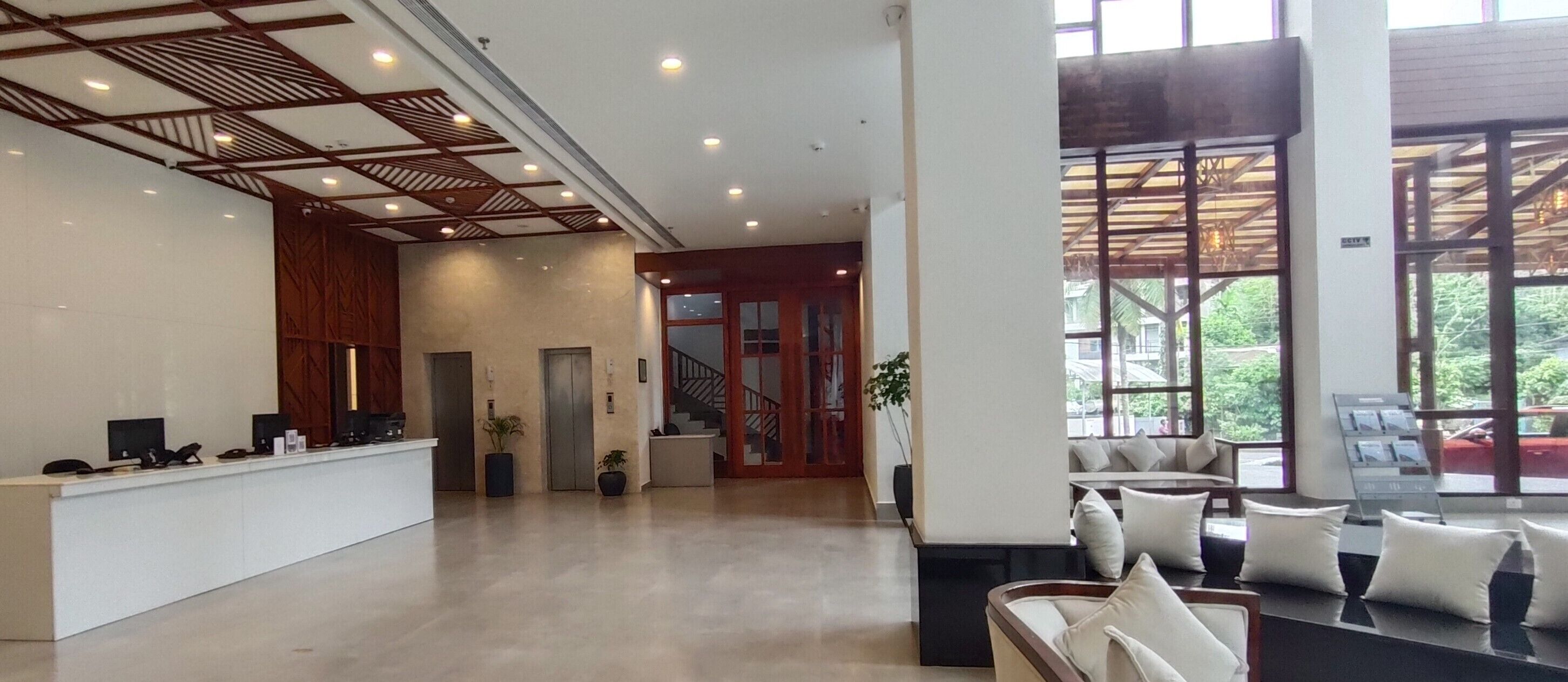 Un vestíbulo amplio con mostrador de recepción, ascensores y una zona de estar con vistas al exterior.