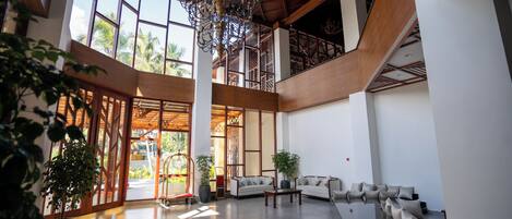 A spacious interior with a high ceiling, large windows, and a central chandelier.
