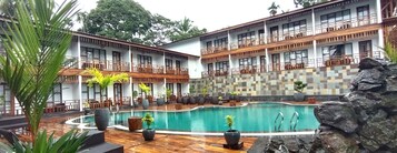 Um hotel com piscina, área de estar externa e parede revestida de azulejos.