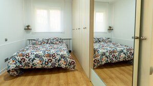 A bedroom with two beds, a large mirror, and a window with blinds. - Apto tranquilo y luminoso con cocina equipada (Santander)