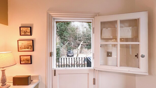 Ein Zimmer mit einer Tür, die auf einen Balkon führt, einer Lampe und drei gerahmten Bildern an der Wand.