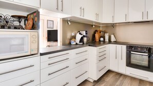 Una cocina moderna con armarios blancos, electrodomésticos de acero inoxidable y un horno empotrado.