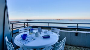 A balcony with a table set for dining, overlooking a calm sea and distant land. - Apartment with balcony overlooking the sea, for 4 (Dinard)