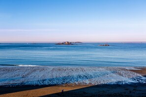 A beach with clear blue water, a sandy shore, and a small island in the distance. - Apartment with balcony overlooking the sea, for 4 (Dinard)