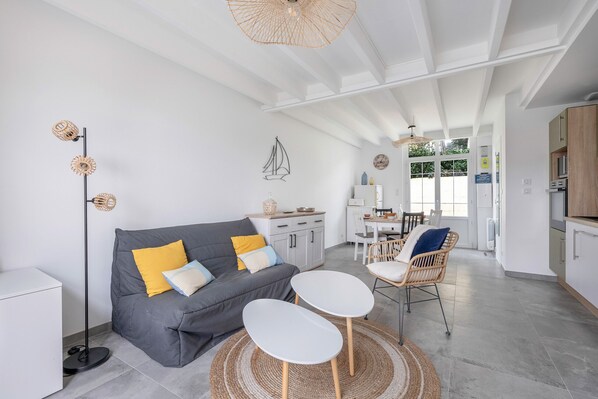 A modern living room with a grey sofa, two white side tables, a floor lamp, and a woven rug. - 450m from beaches, house for 2 adults 2 children (Pornichet)