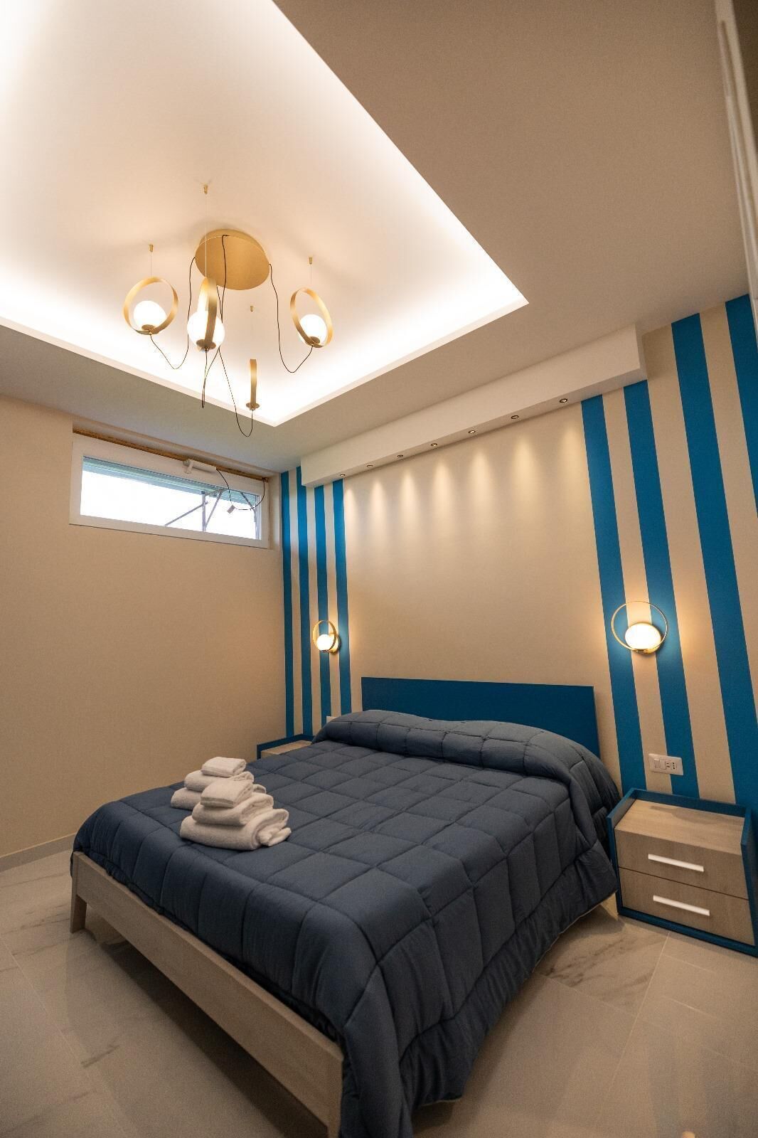 Un dormitorio moderno con cama, mesitas de noche y un tragaluz.