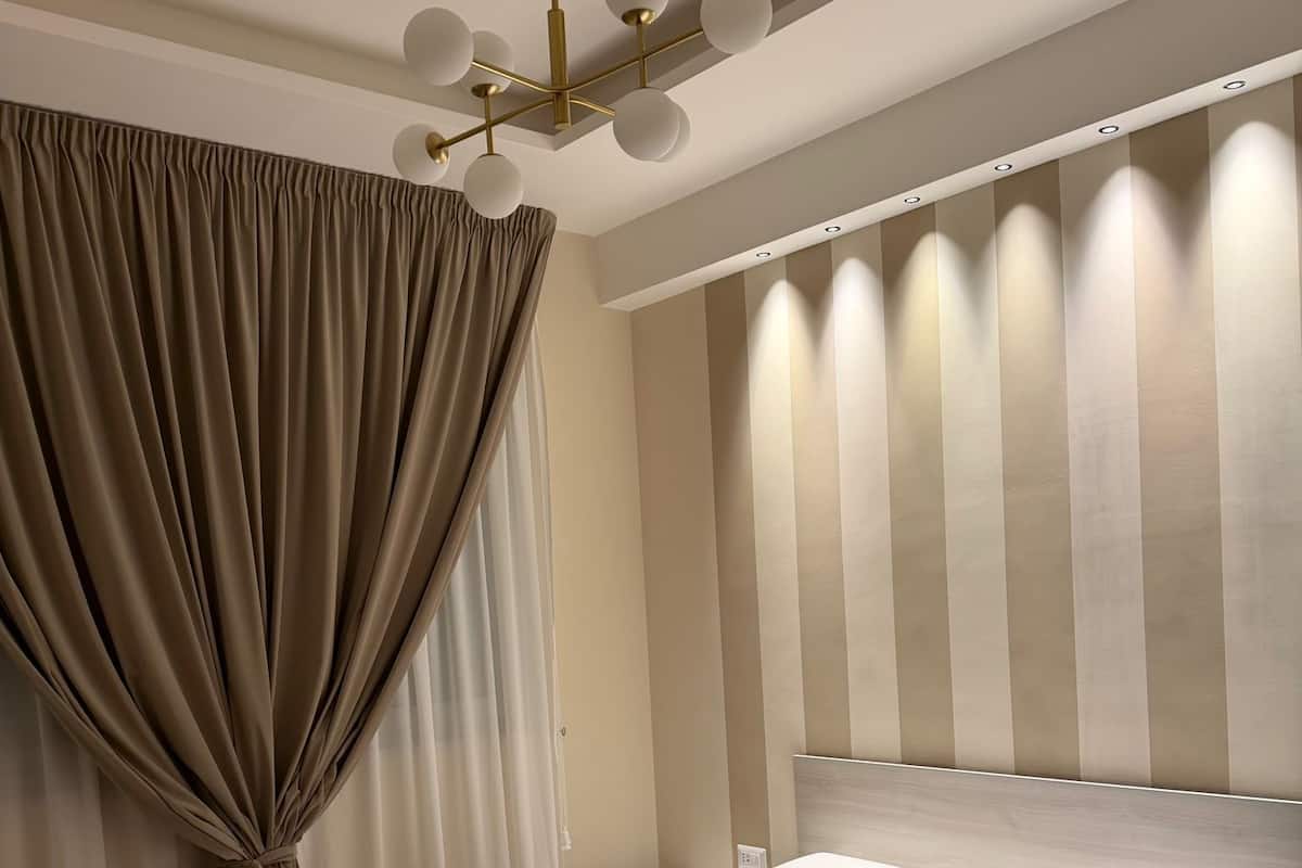 A modern bedroom with a large bed, a bedside table, and a hanging light fixture.