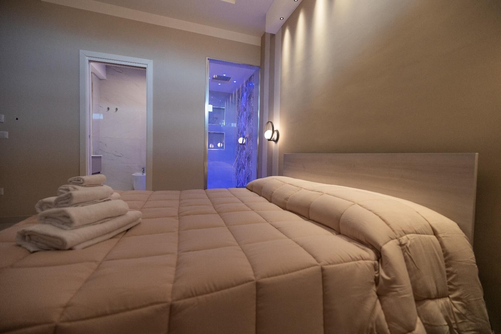 A bedroom with a large bed, a headboard, and a wall-mounted light fixture.