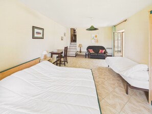 Habitación de hotel con dos camas, un escritorio, una silla, un sofá y una escalera que conduce a un piso superior.