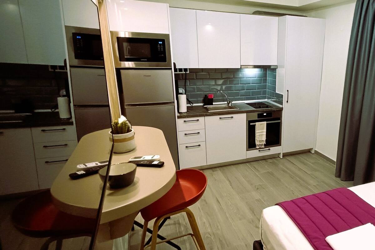 Une chambre d’hôtel de taille réduite comprenant un lit, une petite kitchenette, un coin repas et une salle de bain.