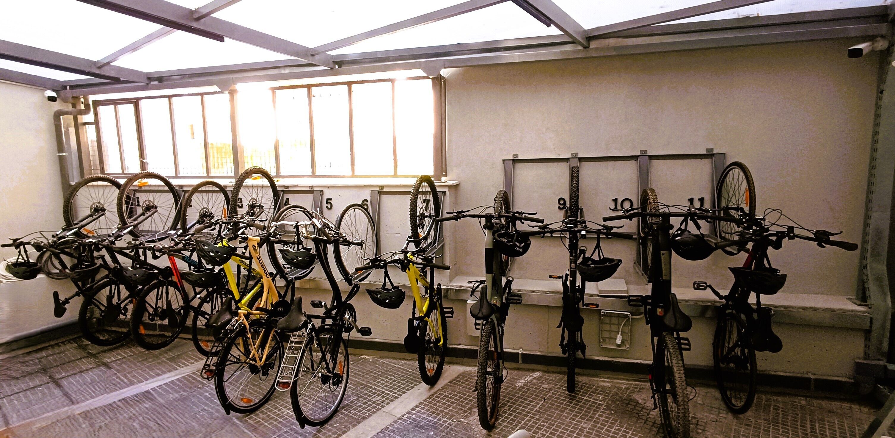 Un espacio cubierto para estacionar bicicletas, con varias bicicletas y cascos.