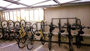 Un espacio cubierto para estacionar bicicletas, con varias bicicletas y cascos.