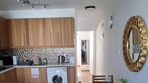 Une cuisine compacte avec des meubles en bois, un lave-linge et un coin repas comprenant une table et des chaises.