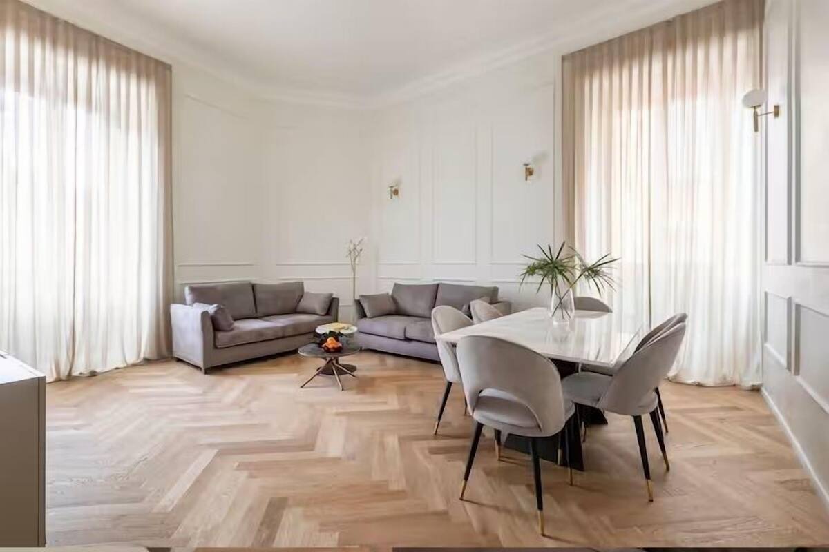 Een moderne woonkamer met een visgraatvloer, een eettafel met stoelen en twee banken.
